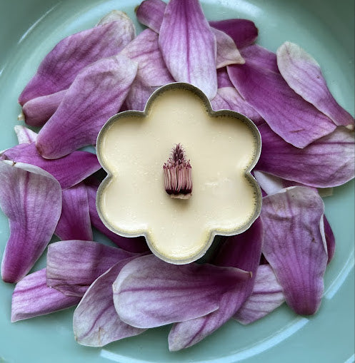 a panna cotta style dessert in a flower-shaped tin, plated amoungst wild flowers.